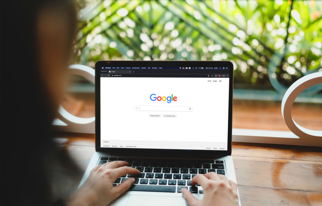 Pessoa utilizando um notebook com a página inicial do Google aberta, representando buscas online e SEO para negócios locais.