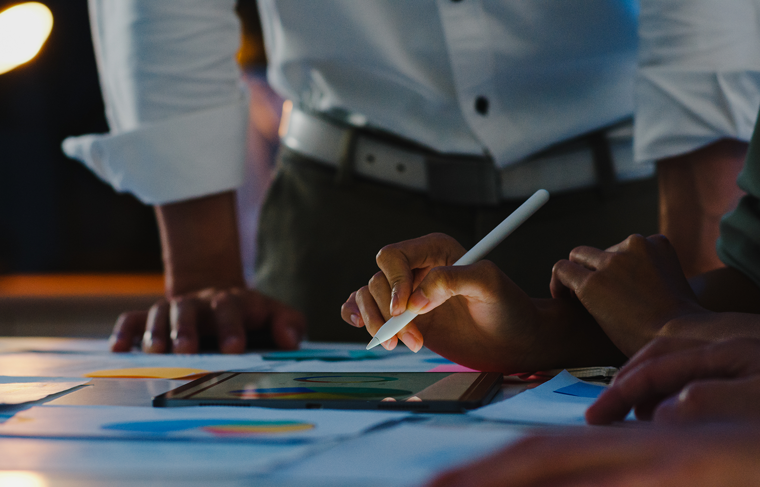 Equipe reunida em torno de uma mesa analisando dados e estratégias em um tablet digital. A cena representa ações de branding voltadas para a construção de valor, posicionamento e fortalecimento da marca no ambiente digital.